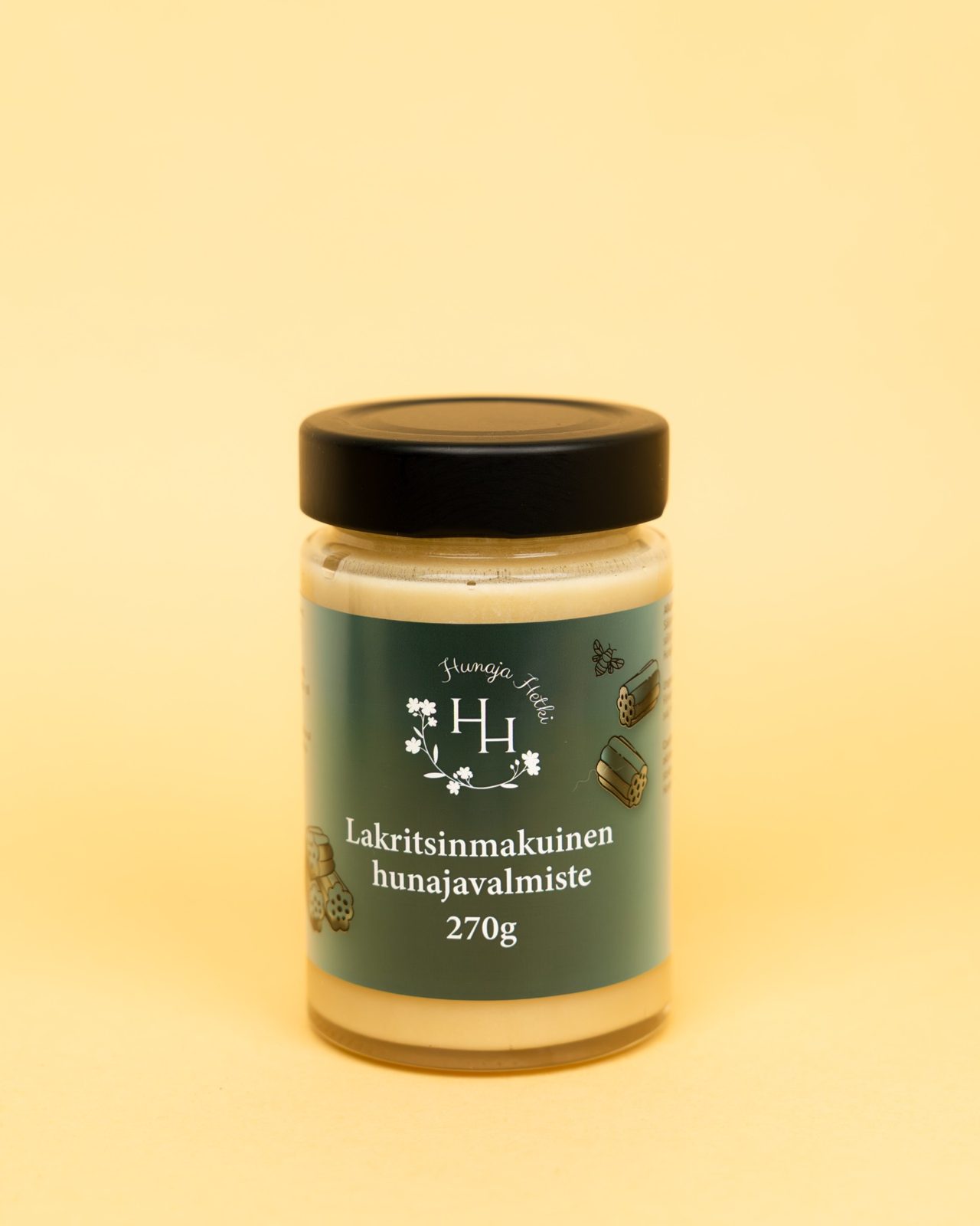 Bilden visar en burk honung med lakritssmak på ljus bakgrund. Etiketten har bilder på lakrits och svart/mörk bakgrund.