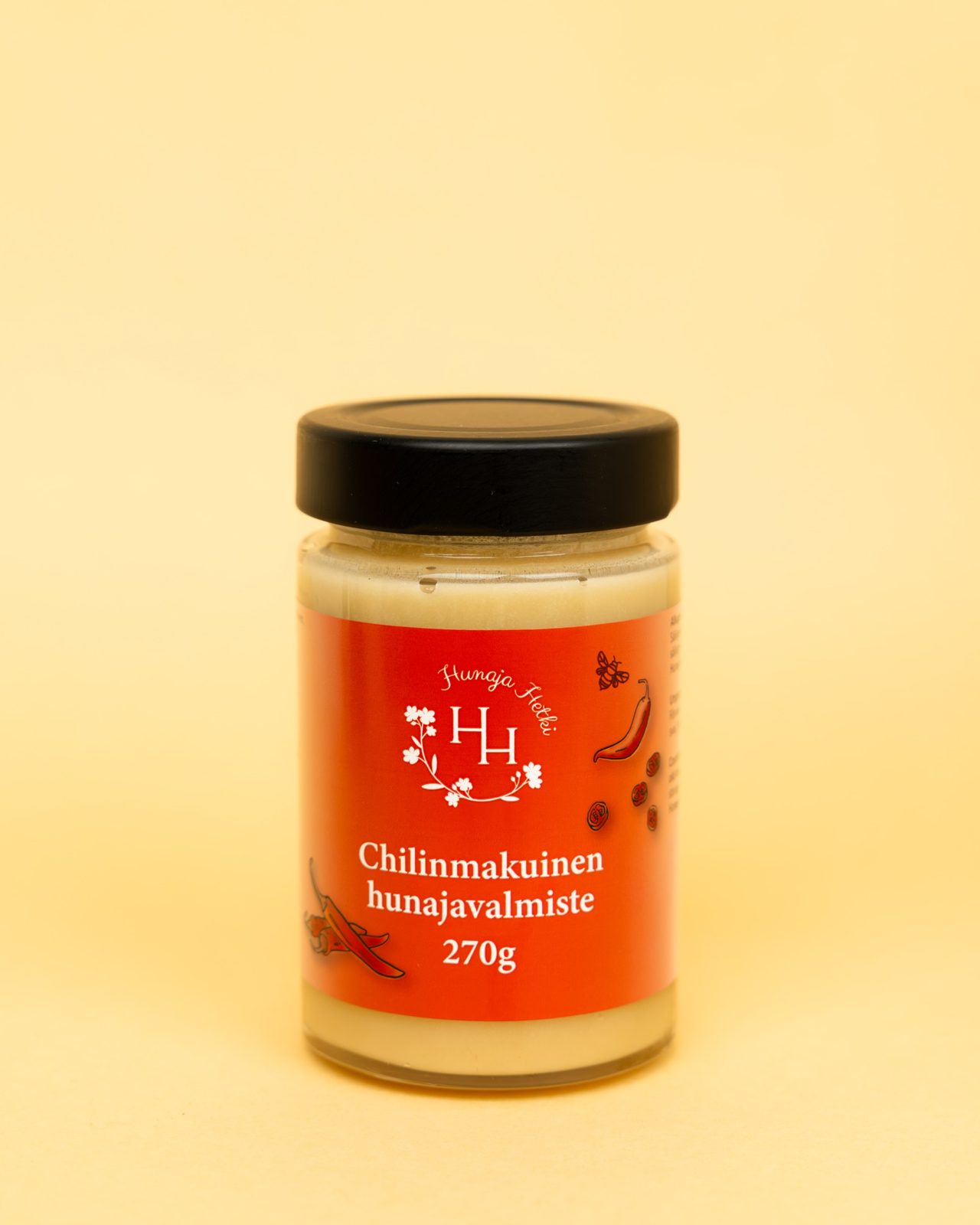 Kuvassa keltaisella taustalla Chilinmakuinen hunajavalmiste. Etiketti on punainen ja siin&auml; on chilin kuva.